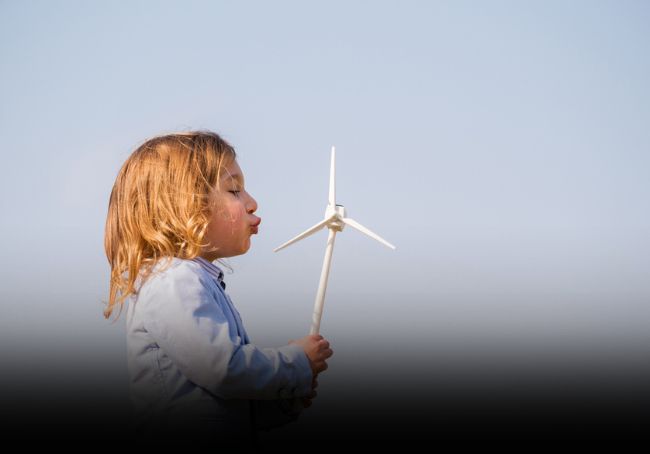 Bambino che soffia su pala eolica giocattolo